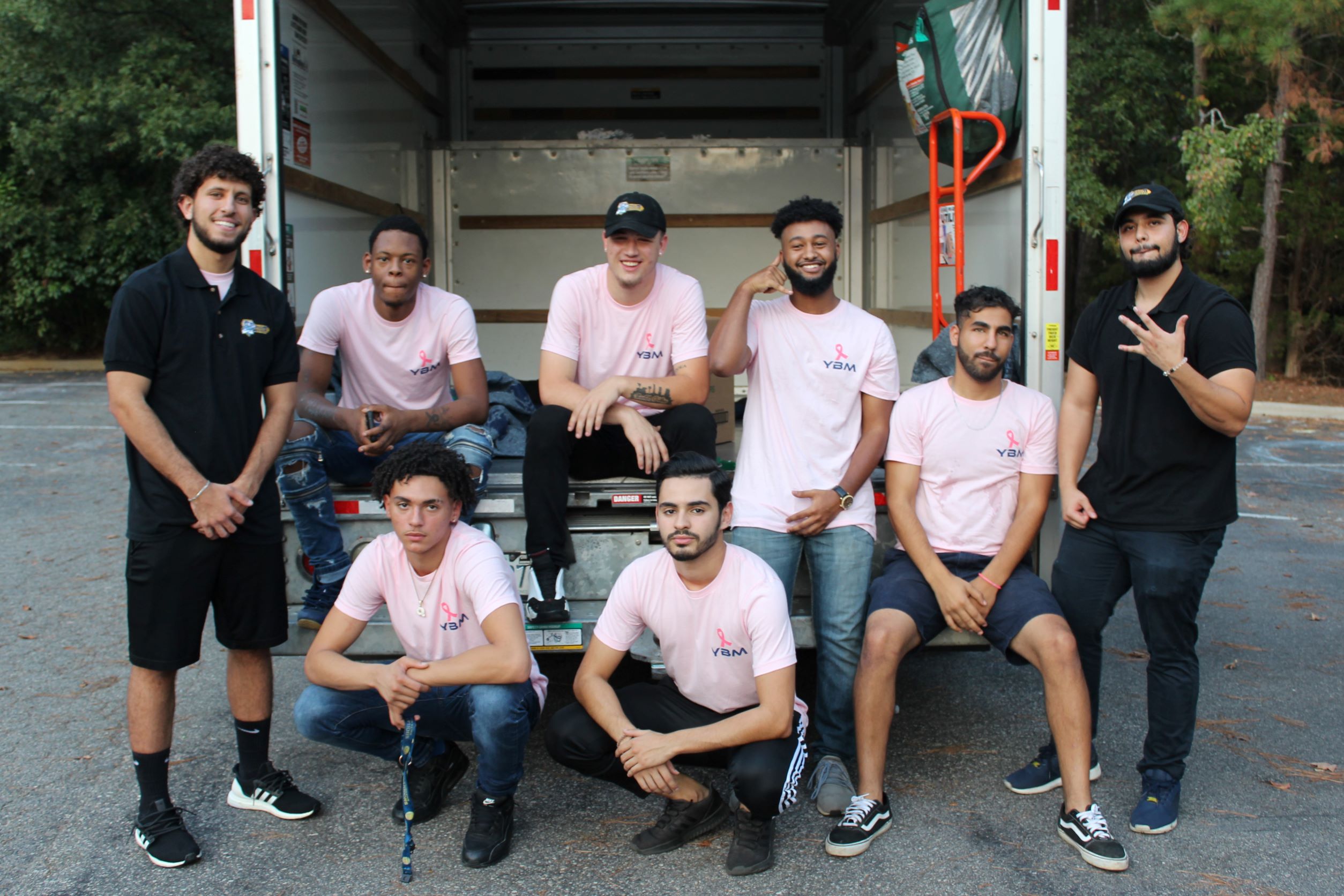 YBM crew members and leaders pose with the breact cancer awareness merch infront of a truck