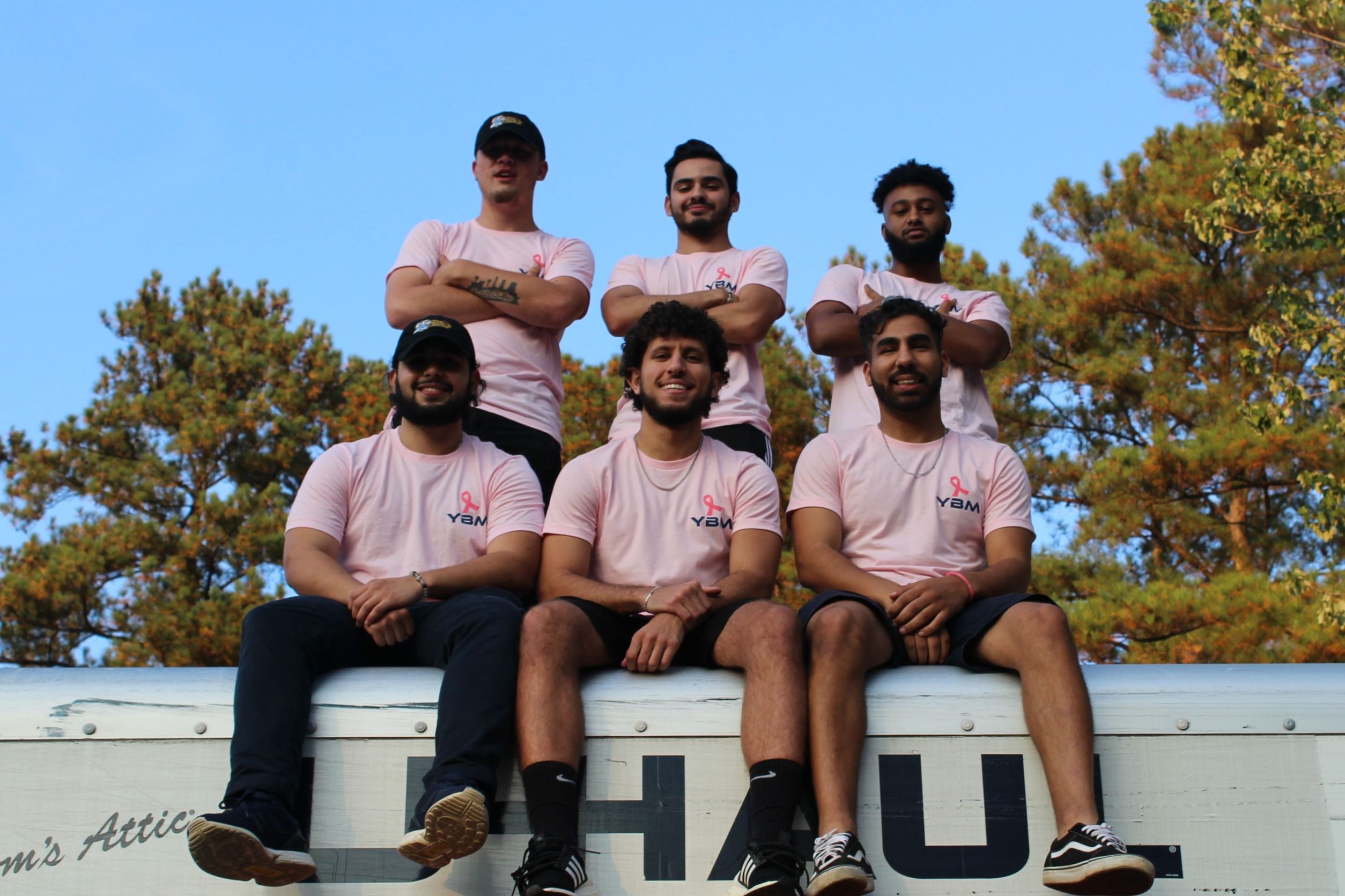 YBM crew members and leaders pose with the breact cancer awareness merch on top of a truck